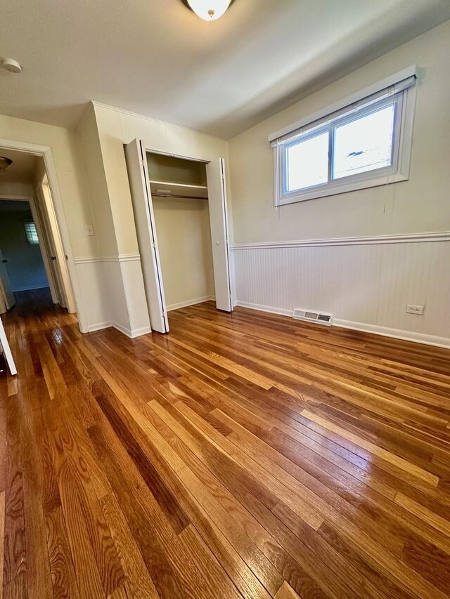 319 Triggs Ave, Elgin, IL 60123 - unfurnished bedroom with wood-type flooring, a closet, and a wainscoted wall