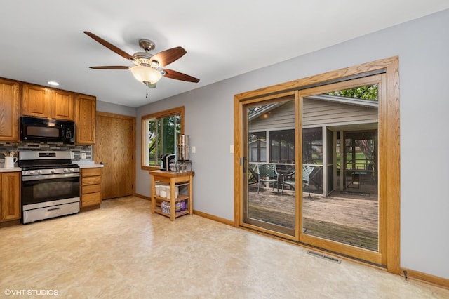 7404 Wooded Shore Dr, Wonder Lake, IL 60097 - kitchen featuring gas range, black microwave, a ceiling fan, and brown cabinets