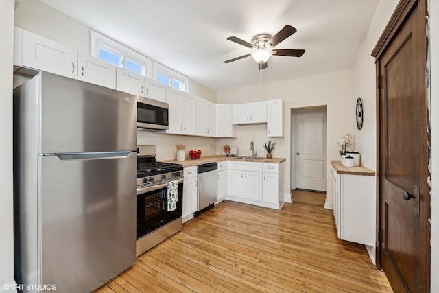 2542 N Long Ave, Chicago, IL 60639 - kitchen featuring appliances with stainless steel finishes, a sink, ceiling fan, light wood-style flooring, and white cabinets