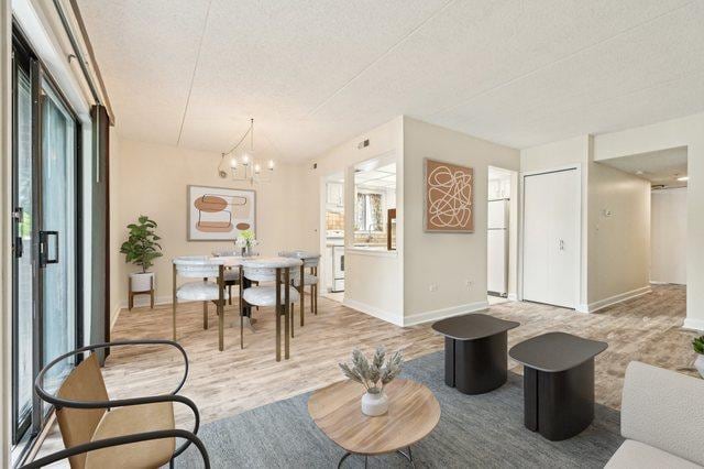 1221 Chalet Rd Unit 101, Naperville, IL 60563 - living area featuring wood finished floors, a chandelier, baseboards, and a textured ceiling
