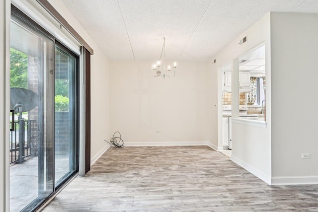1221 Chalet Rd Unit 101, Naperville, IL 60563 - unfurnished room featuring a chandelier, a textured ceiling, light wood-style flooring, and baseboards
