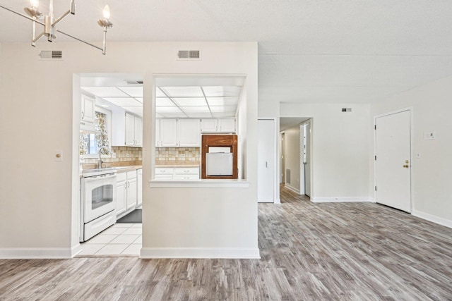 1221 Chalet Rd Unit 101, Naperville, IL 60563 - kitchen with white range with electric stovetop, light wood-type flooring, light countertops, and white cabinetry