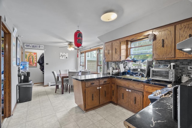 6004 S Keeler Ave, Chicago, IL 60629 - kitchen featuring a peninsula, brown cabinets, backsplash, and under cabinet range hood