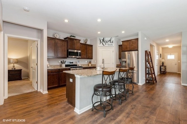 1033 Carolina Ct, Pingree Grove, IL 60140 - kitchen with appliances with stainless steel finishes, a center island with sink, dark wood-style flooring, a kitchen bar, and dark brown cabinets