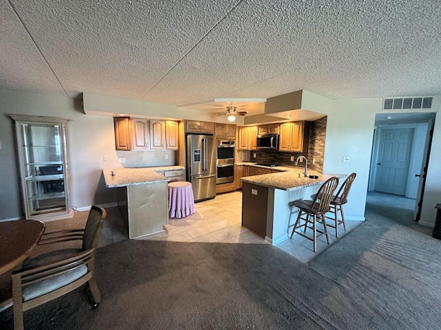 1133 N 7th St Unit 806, Rochelle, IL 61068 - kitchen with appliances with stainless steel finishes, a peninsula, a kitchen bar, tasteful backsplash, and a textured ceiling