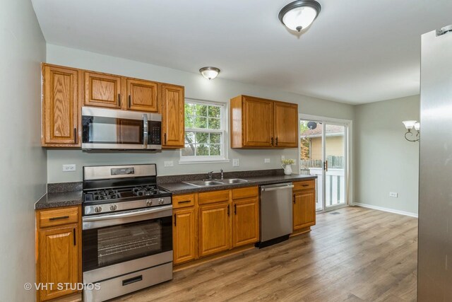 25785 W Hillside Ave, Ingleside, IL 60041 - kitchen featuring stainless steel appliances, a sink, dark countertops, light wood finished floors, and brown cabinets