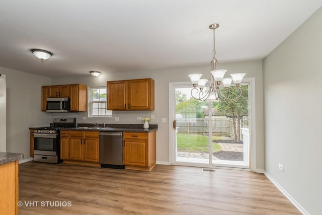 25785 W Hillside Ave, Ingleside, IL 60041 - kitchen featuring stainless steel appliances, dark countertops, brown cabinetry, and a chandelier