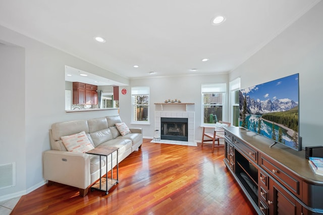 1282 Berkshire Ln, Grayslake, IL 60030 - living area with a tiled fireplace, wood finished floors, baseboards, recessed lighting, and crown molding