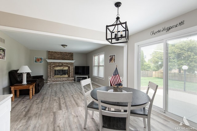 3365 Charlemaine Dr, Aurora, IL 60504 - dining area featuring light wood-style flooring, a fireplace, a chandelier, and baseboards