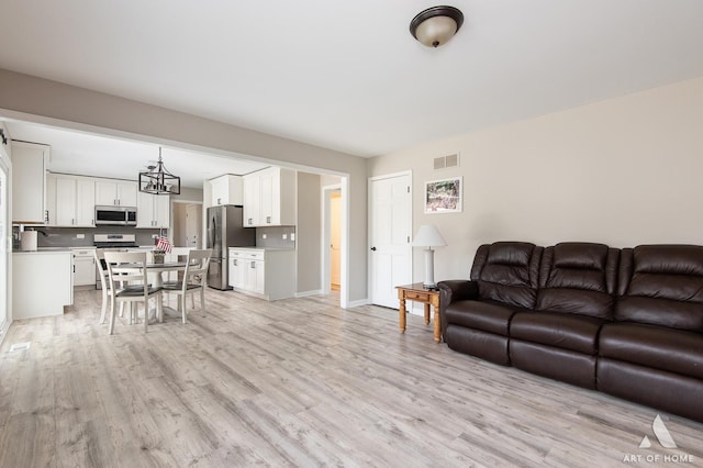 3365 Charlemaine Dr, Aurora, IL 60504 - living room featuring light wood-type flooring, baseboards, and a chandelier