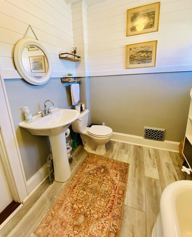 106 Dewey St, Harvard, IL 60033 - bathroom featuring wood finished floors, wooden walls, and toilet