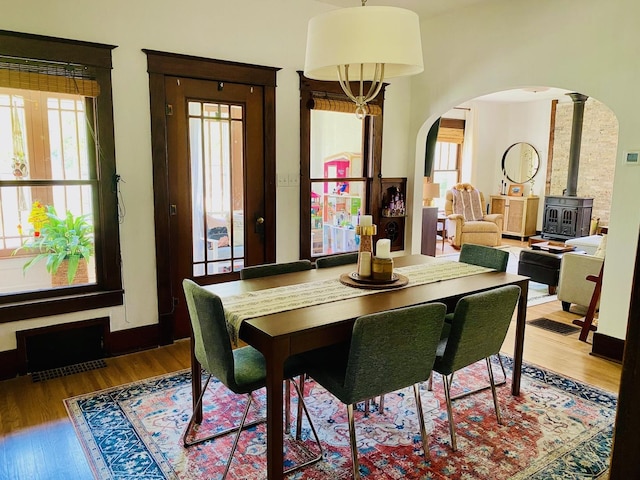 106 Dewey St, Harvard, IL 60033 - dining space with arched walkways, wood finished floors, healthy amount of natural light, and a wood stove