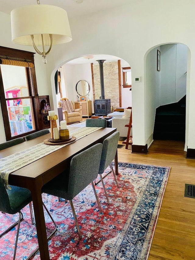 106 Dewey St, Harvard, IL 60033 - dining area with arched walkways, a wood stove, wood finished floors, stairway, and baseboards