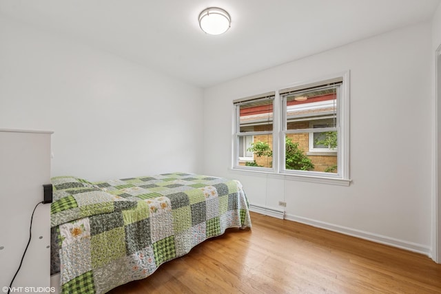 5513 Mulford St, Skokie, IL 60077 - bedroom with wood finished floors, baseboards, and baseboard heating