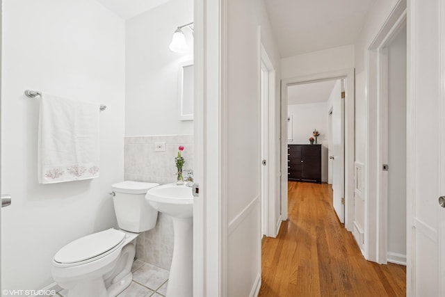 5513 Mulford St, Skokie, IL 60077 - bathroom with toilet, wood finished floors, tile walls, and a wainscoted wall