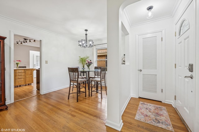 5513 Mulford St, Skokie, IL 60077 - dining room with light wood-style flooring, a chandelier, ornamental molding, arched walkways, and baseboards