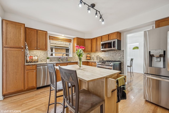 5513 Mulford St, Skokie, IL 60077 - kitchen with stainless steel appliances, wooden counters, a sink, light wood-style floors, and tasteful backsplash