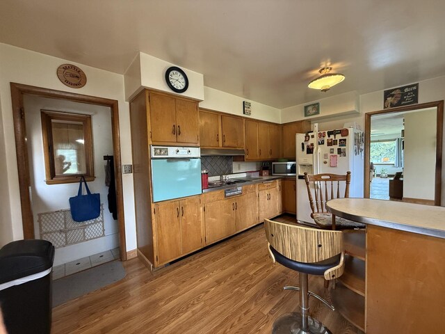 612 S 1st Ave, Forreston, IL 61030 - kitchen featuring white appliances, wood finished floors, brown cabinetry, and tasteful backsplash