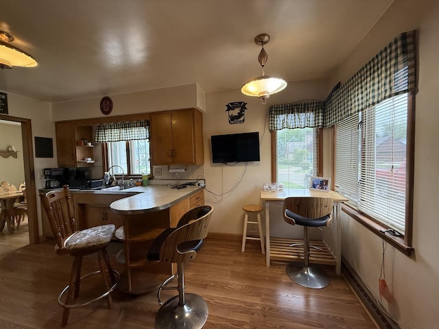 612 S 1st Ave, Forreston, IL 61030 - kitchen featuring wood finished floors, a peninsula, a sink, baseboards, and brown cabinetry
