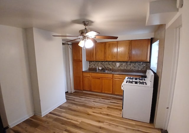 254 E 92nd St, Chicago, IL 60619 - kitchen featuring white range with gas stovetop, ceiling fan, light wood finished floors, and backsplash