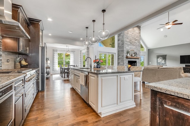 7166 Clubhouse Dr, Yorkville, IL 60560 - kitchen with wall chimney exhaust hood, a sink, a fireplace, dark brown cabinetry, and ceiling fan
