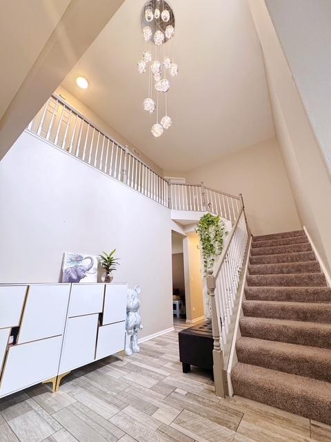 11319 Maplewood Dr, Plainfield, IL 60585 - staircase with a high ceiling, a chandelier, wood finished floors, baseboards, and recessed lighting