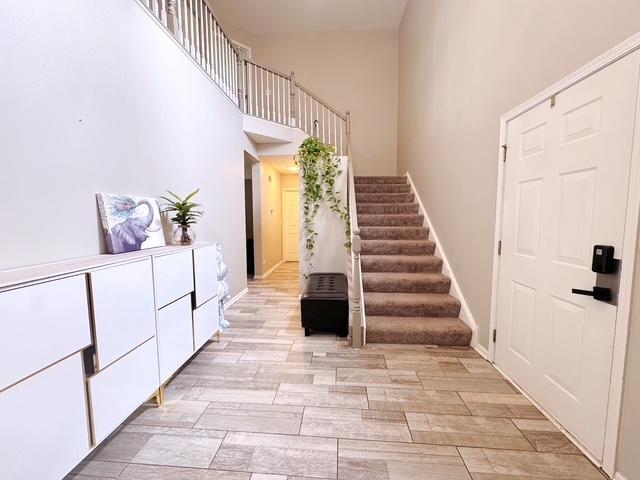 11319 Maplewood Dr, Plainfield, IL 60585 - foyer entrance featuring stairs, a high ceiling, baseboards, and light wood-style floors