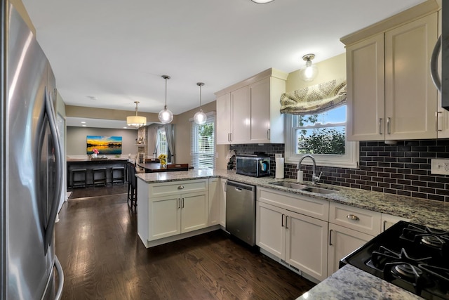 562 Revere Ave, Westmont, IL 60559 - kitchen featuring stainless steel appliances, a peninsula, dark wood-style flooring, decorative backsplash, and decorative light fixtures