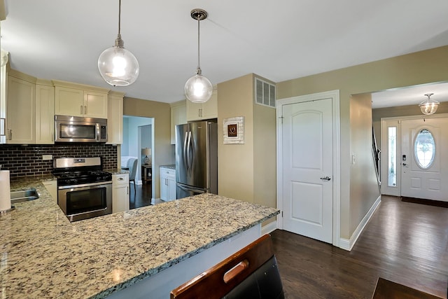 562 Revere Ave, Westmont, IL 60559 - kitchen with stainless steel appliances, light stone countertops, dark wood finished floors, tasteful backsplash, and a peninsula