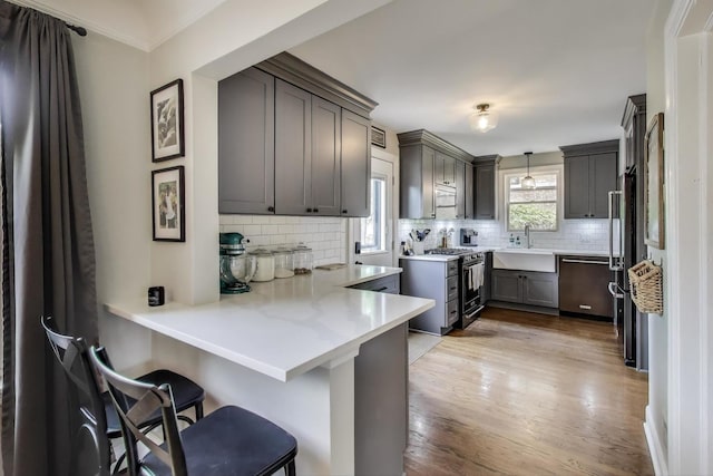 9906 S Saint Louis Ave, Evergreen Park, IL 60805 - kitchen featuring stainless steel appliances, a peninsula, tasteful backsplash, wood finished floors, and a sink