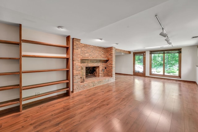 24721 S Walnut St, Crete, IL 60417 - unfurnished living room featuring track lighting, a brick fireplace, and wood finished floors