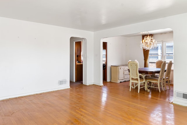 8952 S E End Ave, Chicago, IL 60617 - dining room featuring arched walkways, a chandelier, light wood-type flooring, and baseboards