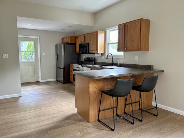 123 N Chicago Ave, Ladd, IL 61329 - kitchen with appliances with stainless steel finishes, a sink, light wood-type flooring, a kitchen bar, and dark countertops