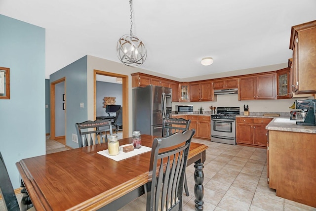 601 High Grove Dr, Minooka, IL 60447 - kitchen with stainless steel appliances, under cabinet range hood, light countertops, a chandelier, and brown cabinets