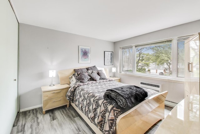 2700 E Bel Aire Dr Unit 202, Arlington Heights, IL 60004 - bedroom with baseboard heating, light wood-style floors, an AC wall unit, and baseboards