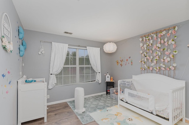 310 Cascade Ln Unit 310, Oswego, IL 60543 - bedroom featuring wood finished floors, baseboards, and a crib
