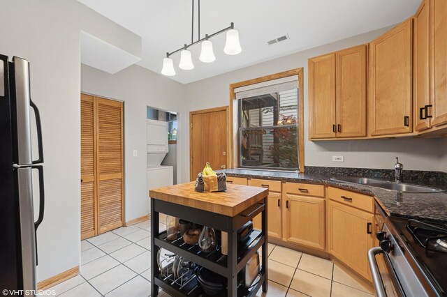 2235 N Saint Louis Ave Unit 1, Chicago, IL 60647 - kitchen with stacked washer / dryer, appliances with stainless steel finishes, a sink, and light tile patterned floors