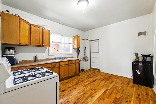 1738 N Latrobe Ave, Chicago, IL 60639 - kitchen with white gas range, brown cabinetry, light wood-style flooring, and a sink