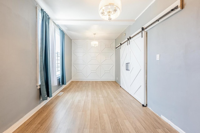 7115 S Rockwell St, Chicago, IL 60629 - empty room with a barn door, light wood-style flooring, baseboards, and a chandelier