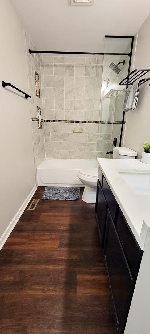1427 Hampton Ln, Schaumburg, IL 60193 - full bathroom featuring tub / shower combination, vanity, toilet, wood finished floors, and baseboards