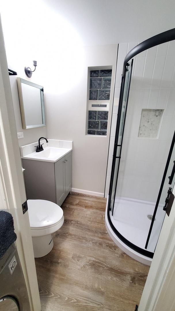 1427 Hampton Ln, Schaumburg, IL 60193 - full bath with a shower stall, wood finished floors, toilet, vanity, and baseboards