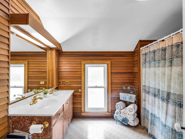 611 S Lynn St, Champaign, IL 61820 - full bathroom featuring vaulted ceiling, double vanity, wooden walls, and a shower with shower curtain