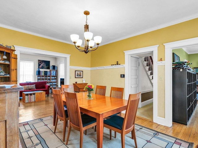 611 S Lynn St, Champaign, IL 61820 - dining space featuring light wood finished floors, a chandelier, ornamental molding, and stairs
