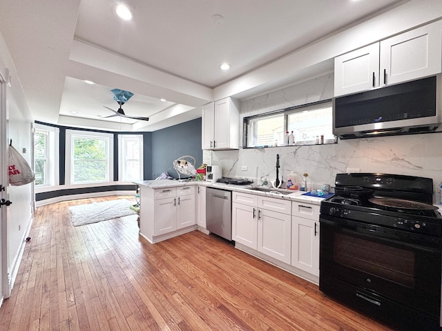 3316 W Flournoy St, Chicago, IL 60624 - kitchen featuring stainless steel appliances, a peninsula, a tray ceiling, light wood-style flooring, and white cabinets