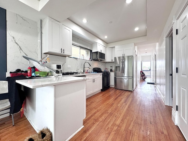 3316 W Flournoy St, Chicago, IL 60624 - kitchen featuring black appliances, healthy amount of natural light, a peninsula, light wood finished floors, and recessed lighting