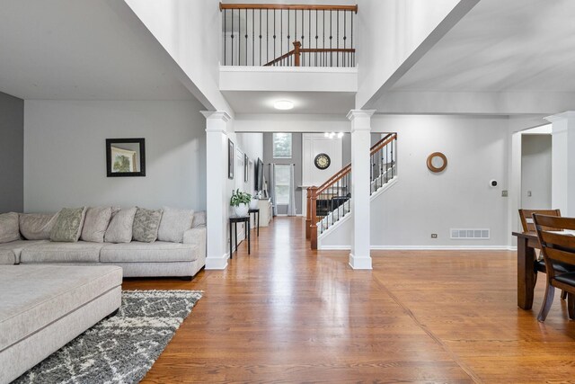 24723 W Champion Dr, Plainfield, IL 60585 - living room featuring decorative columns, wood finished floors, a high ceiling, stairway, and baseboards