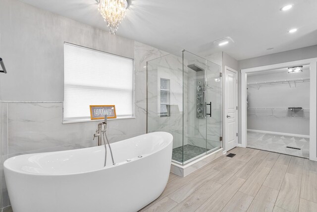 24723 W Champion Dr, Plainfield, IL 60585 - bathroom featuring a marble finish shower, a soaking tub, wood finished floors, a walk in closet, and a chandelier