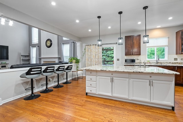 24723 W Champion Dr, Plainfield, IL 60585 - kitchen featuring light wood-style flooring, plenty of natural light, a center island with sink, light stone countertops, and recessed lighting