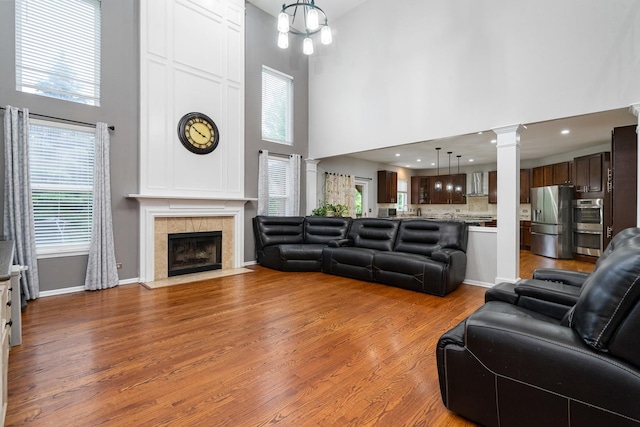 24723 W Champion Dr, Plainfield, IL 60585 - living area featuring a high ceiling, wood finished floors, plenty of natural light, decorative columns, and a tiled fireplace