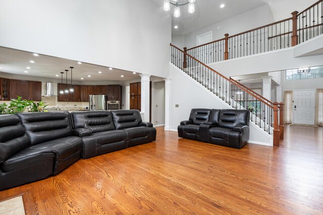 24723 W Champion Dr, Plainfield, IL 60585 - living area featuring decorative columns, light wood finished floors, a towering ceiling, recessed lighting, and stairway